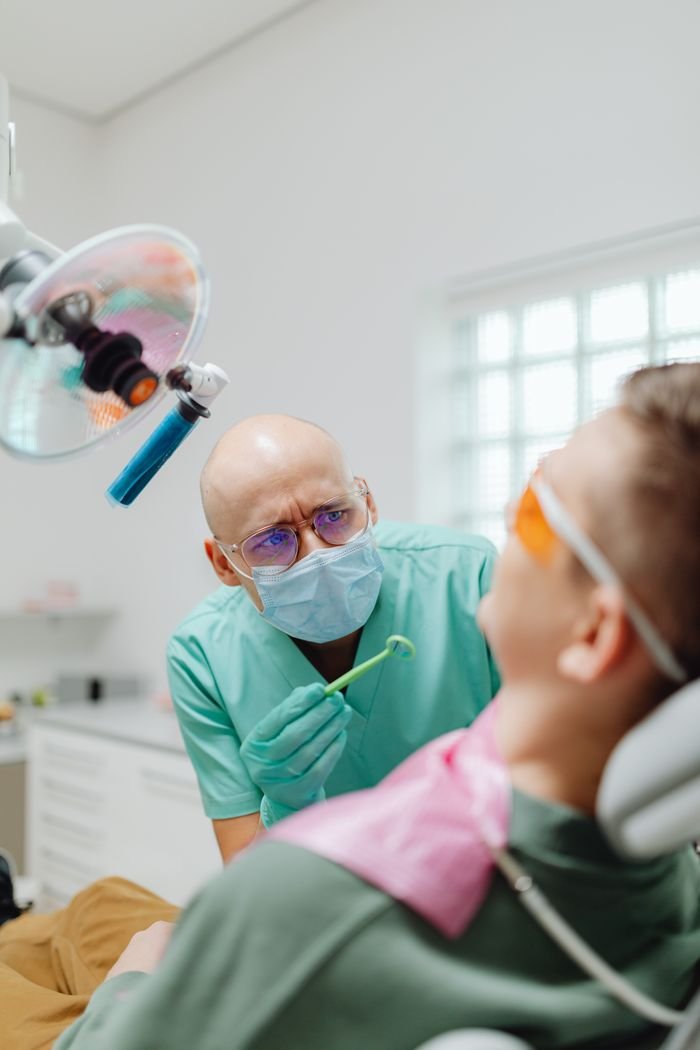 Home Dentist with a surgical mask examining a patient in a modern dental clinic.